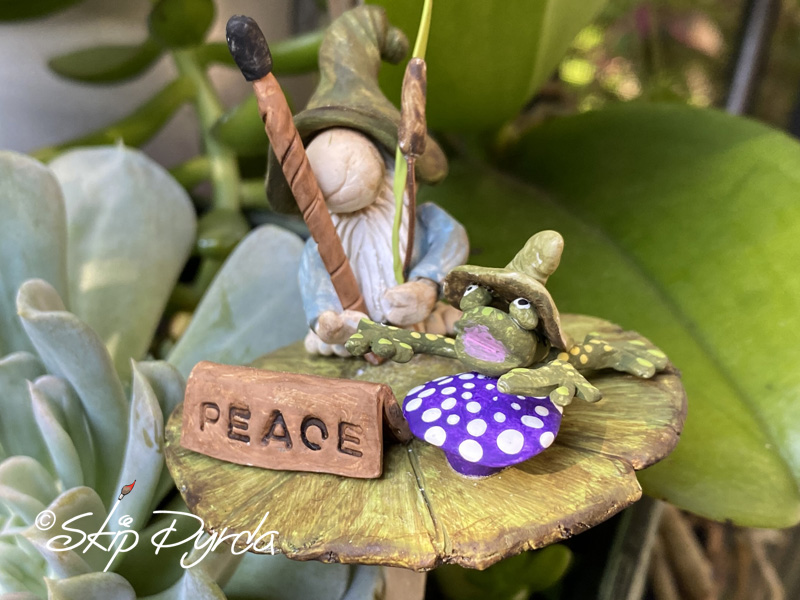 Painted clay gnome figurine on a lily pad with a frog
